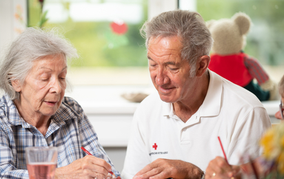 Seniorenbetreuung_02 - © Rk NÖ/Florian Schodritz Ein älterer freiwilliger Mitarbeiter des Roten Kreuzes Niederösterreich hilft einer Seniorin ein Blatt auszufüllen.