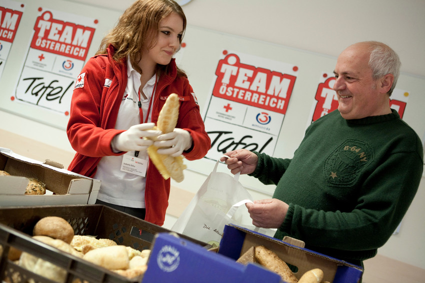 Team Österreich Tafel - © ÖRK/Nadja Meister Auf dem Bild eine freiwillige die gerade Brot an einen Herren ausgiebt