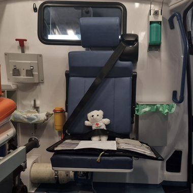 Erklärbär Bärli sitzt in einem Rettungswagen. Vor ihm liegt eine Mappe mit Protokollen zur Einsatzdokumentation.
