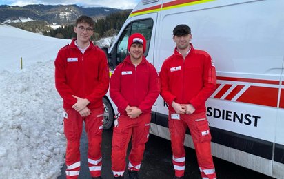 Drei Sanitäter vor Rotkreuzauto