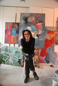 Frau Lessel sitzt vor ihren Kunstwerken