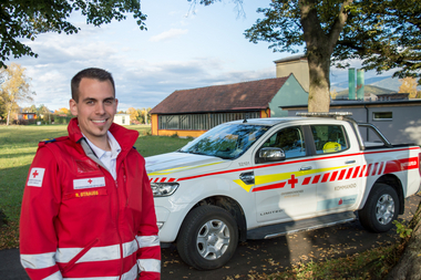 Robert Strauss - Offizier vom Dienst - steht in Rotkreuz-Einsatzuniform vor einem Kommandofahrzeug.