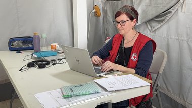 Rotkreuz Mitarbeiterin vor dem Laptop