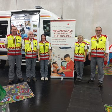 Das Team der Kidsambulanz steht in Rotkreuz-Uniformen vor der Kidsambulanz