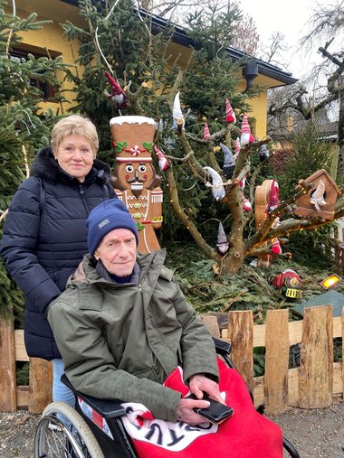 Werner und Edith vor der Dekoration des Hellbrunnner Adventzaubers. Im Hintergrund ist eine Figur eines großen Nussknackers aus Lebkuchen zu sehen.