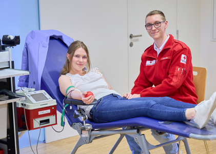 Eine junge Frau spendet Blut und wird dabei von einem Rotkreuz Mitarbeiter betreut.