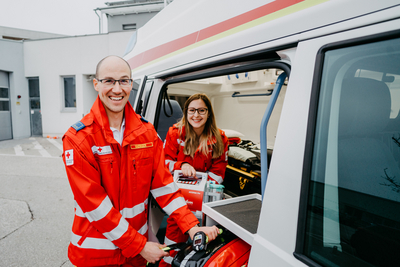 Zwei Sanitäter grinsen aus einem Rettungsauto
