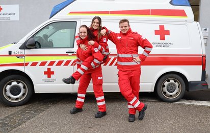 3 Rettungssanitäter vor einem Rettungswagen