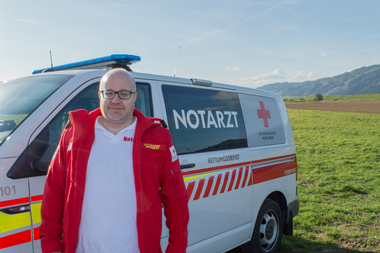 OA Dr. Markus Gschanes - Bezirksrotkreuzarzt - steht in Rotkreuz-Einsatzuniform vor einem Notarzteinsatzfahrzeug im Freien.
