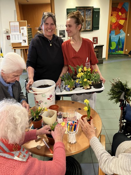 Glückliche Mitarbeiter:innen und Bewohner:innen beim Binden