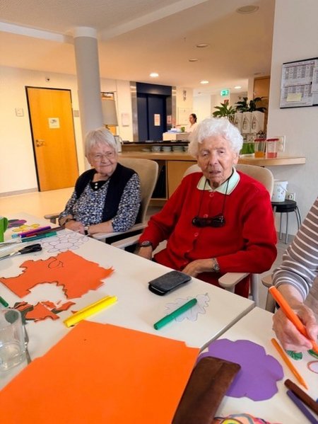Bewohnerinnen des Seniorenwohnhauses helfen bei der Gestaltung der Wände mit.