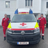 Zwei Zivildiener stehen rechts und links neben einem Rettungsauto