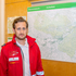 Mag. Philipp Nowak - Mitarbeiter des Bezirksrettungskommandos - steht in Rotkreuz-Einsatzuniform vor einer Karte des Einsatzgebietes.