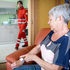Rotkreuz-Sanitäter helfen einer Dame, nachdem sie auf ihrem Rufhilfe-Armband den Notrufknopf gedrückt hat.