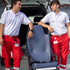Zwei Zivildiener in Uniform stehen mit einem Tragsessel vor einem Rettungsauto, das hinten geöffnet ist