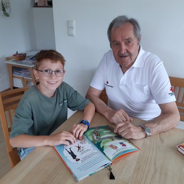 Lesecoach Williband mit einem Kind dem er beim Lesenlernen hilft.