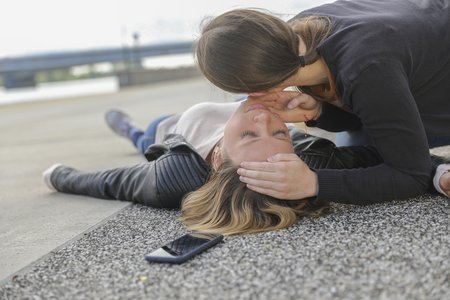 Eine Frau überprüft den Atem einer am Boden liegenden Frau