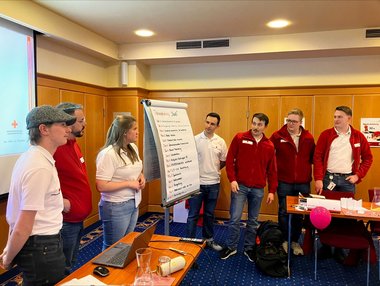 Die Teilnehmerinnen stehen um ein Flipchart versammelt, auf dem eine Jahresplanung zu sehen ist.