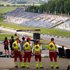 Man sieht Sanitäter:innen von hinten. Sie stehen erhöht und überblicken einen Teil des Red Bull Rings. Es sind auch einige Motorsportfans im Bild.