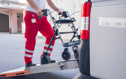 © Österreichisches Rotes Kreuz (ÖRK) / Julian Ringler Ein Rotkreuz-Mitarbeiter lädt eine Gehhilfe in einen Transport Wagen ein.