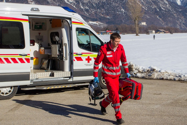 Ein Rotkreuz Sanitäter kommt am Unfallort an. In seiner Hand befindet sich ein Notfallrucksack