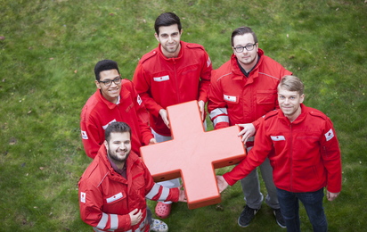 Fünf Zivildiener halten ein Rotes Kreuz