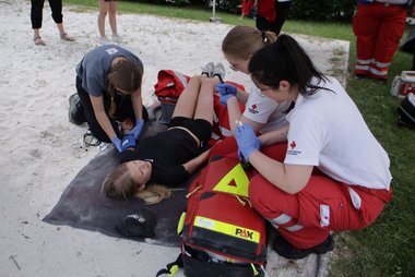 Rettungssanitäter:innen und JRK-Kinder versorgen eine verletzte Person bei einem Szenario