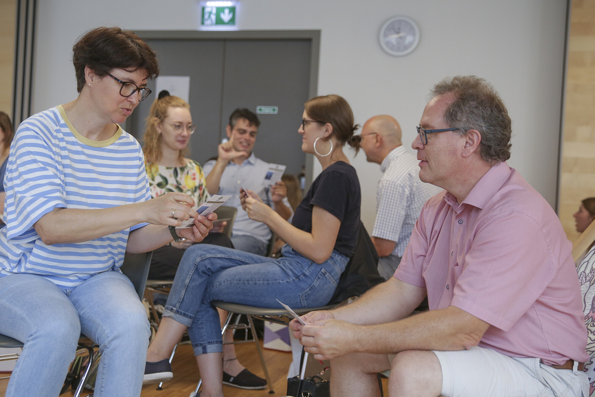im Team arbeitet eine Gruppe von Menschen an einem Thema. Eine Frau und ein Mann leiten das Team
