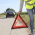 Person mit Warndreieck vor PKW