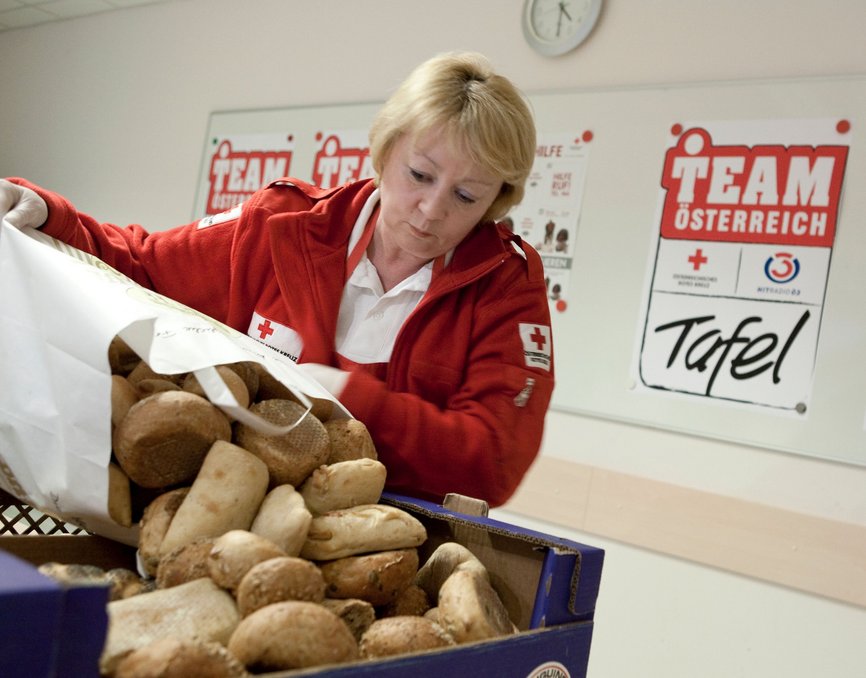 Team Österreich Tafel - © Österreichisches Rotes Kreuz Nadja Meister eine Team Österreich Tafel Mitarbeiterin vom Roten Kreuz füllt Brot und Gebäck in eine Schachtel