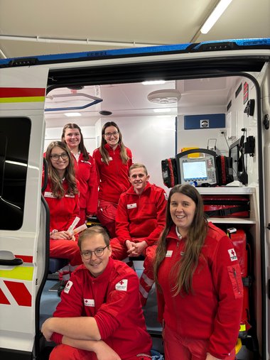 6 Sanitäter:innen Sitzen im Rettungsauto für ein Foto nach der erfolgreich abgelegten NKV-Prüfung