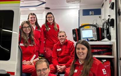 6 Sanitäter:innen Sitzen im Rettungsauto für ein Foto nach der erfolgreich abgelegten NKV-Prüfung