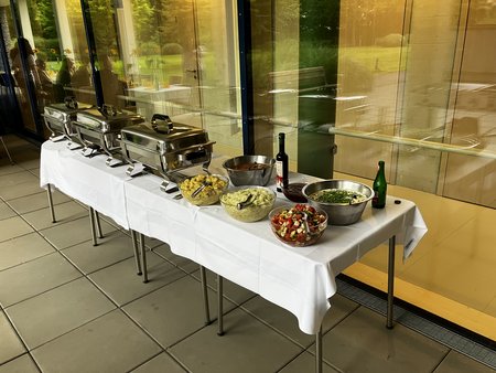 Tische mit Essen in Speisewärmern, Salaten und Soßen