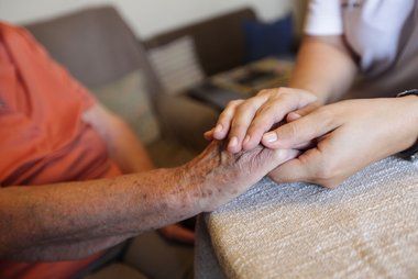 © ÖRK/Markus Hechenberger Nahaufnahme von Händen: eine Rotkreuz-Mitarbeiterin hält die Hand einer älteren Dame.