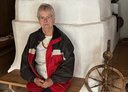 Ausflugsteilnehmerin sitzt neben einem alten Spinnrad.