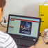 Frau sitzt vor dem Laptop und betrachtet die Einstiegsseite zum Online-Kurs