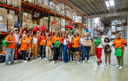 Gruppenfoto von Amazon und Rotkreuz Mitarbeitenden in Lagerhalle