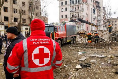 Ein Mitarbeiter des Ukrainischen Roten Kreuzes steht vor den Trümmern eines Wohnhauses