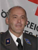 Finanzreferent HR DI Heribert Bogensperger - © Rotes Kreuz Knittelfeld HR DI Heribert Bogensperger - Finanzreferent - in Ausgangsuniform vor einer Rotkreuz-Standarte.