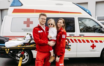 Engagement beim Roten Kreuz wird zur Liebe fürs Leben: Robert und Lisa mit Tochter Sophie vor einem Rettungswagen