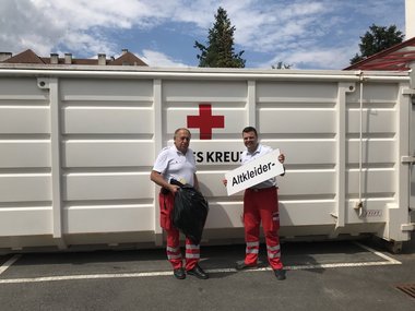 Die ehemalige Altkleidersammlung der Bezirksstelle. Zwei Mitarbeiter stehen vor dem Container im Innenhof der Bezirksstelle.