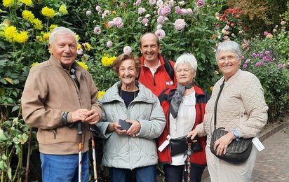 Reiseteilnehmer:innen samt Begleiter vor blühenden Stäuden.