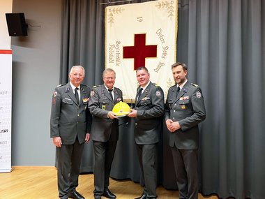 Gruppenaufnahme von links mit Werner Aufmesser, Gerhard Wechselberger, Markus Moser und Stefan Herbst. Wechselberger und Moser halten einen Rotkreuzhelm und ein Funkgerät.