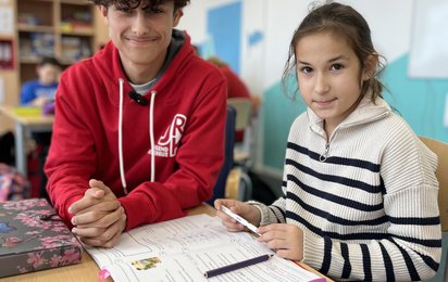 Felix und ein Kind beim Hausaufgaben machen.