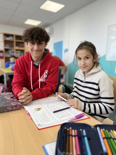 Felix und ein Kind beim Hausaufgaben machen.