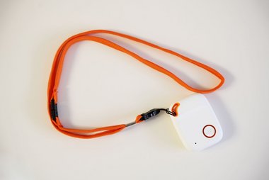 Weißer Notfall-Tracker mit SOS-Knopf und orangem Umhängeband.