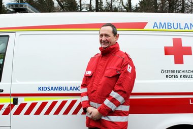 Peter Schober, Leiter des Rotkreuz-Museums und Mitinitiator der Kinder-Ambulanz, steht in Rotkreuz-Uniform vor der Kidsambulanz