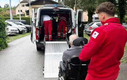 Sanitäter stehen mit einem Patienten vor einem Rettungswagen