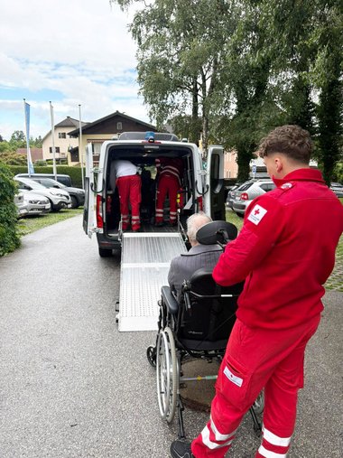 Sanitäter stehen mit einem Patienten vor einem Rettungswagen