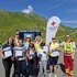 Erste-Hilfe-Kursteilnehmer:innen mit Rettungssanitäter:innen vor eine Rotkreuz-Fahne